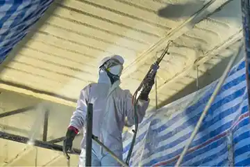 A worker coating the roof with foam
